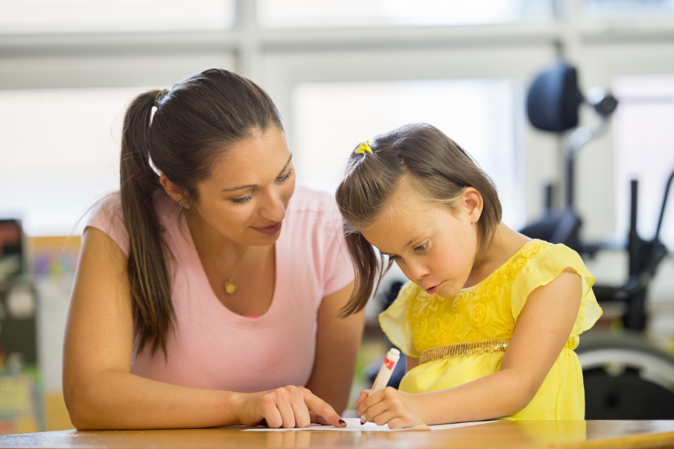 Teacher works with child on writing skills.
